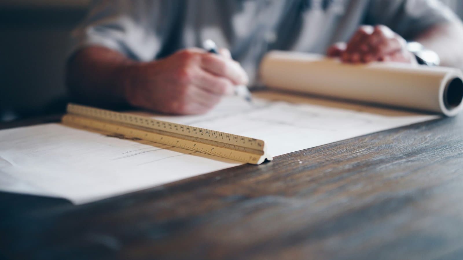 Plans d’architecture déroulés sur une table de travail lors de l’étude de faisabilité d’un projet.